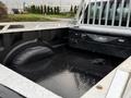 A 2017 Ford F-350 SD truck bed with a black spray-on liner and a storage box featuring a diamond plate design on the floor.