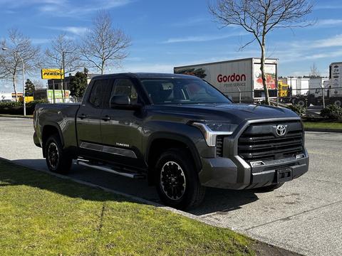 A 2023 Toyota Tundra pickup truck with a dark gray exterior and black rims parked on the street