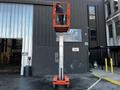 A 2000 JLG 12SP aerial lift with an operator standing in the elevated platform surrounded by a metal structure