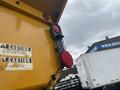 A yellow truck bed with caution signs attached and red lights on the side