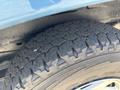 Close-up of a rugged tire with deep treads designed for off-road traction mounted on a blue vehicle