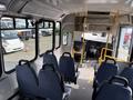 Interior view of a 2018 Chevrolet Express with rows of blue seats two yellow poles and the driver's area visible