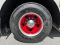 Close-up of a large black tire with a shiny silver hubcap featuring a red outer rim on a fire truck from 2006