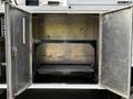 A 2016 Ford F-550 vehicle with open double doors revealing an empty metallic storage compartment inside
