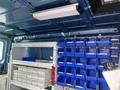 Interior of a 2010 Ford Econoline featuring storage shelves with blue bins and drawers for organizational use