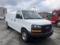 A white 2022 GMC Savana van with a sleek design, featuring a black front grille and chrome wheels, is prominently displayed in the foreground