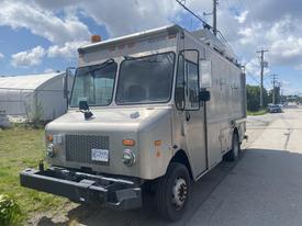 A 2007 Morgan Olson Workhorse W42, a box truck with a silver exterior, equipped with utility lights and a front grill, facing forward on a roadway