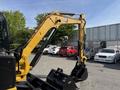 A 2022 Caterpillar 306 excavator featuring a yellow arm and bucket attachment designed for digging and heavy lifting tasks
