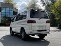 A 2003 Mitsubishi 7 Passenger Van in white with the word DELICA on the side and chrome accents visible on the rear and wheels