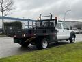 A 2015 Ford F-550 flatbed truck with a black flatbed and tool box visible at the rear and safety lights mounted on top