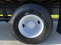 Close-up of a black tire mounted on a white rim belonging to a 2016 Freightliner M2 106 with visible tread pattern and wheel lug nuts