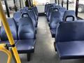 Interior view of a 2018 Chevrolet Express bus showcasing rows of blue upholstered seats with grab handles on the backs