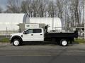 A white 2021 Ford F-550 with a flatbed trailer attached is parked on the street