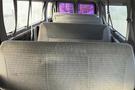 Interior view of a 2002 Ford Econoline showing empty benches in the cargo area with gray upholstery and seatbelts attached