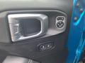 Interior door panel of a 2020 Jeep Wrangler featuring a silver handle power window controls and side mirror adjustment buttons