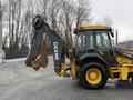 A 2011 John Deere 310SJ 4x4 Wheel Loader with an extended hoe and a 4 in 1 bucket positioned in a working stance