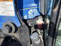 Close-up of a 2010 New Holland T4050 tractor's engine compartment showing the hydraulic components and warning label