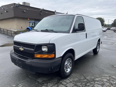 A white 2014 Chevrolet Express van with a black grill and chrome wheels parked in a lot