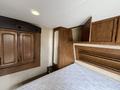 Interior of a 2013 Outdoor Wind River with a wooden cabinet and a bed frame featuring a partially stripped mattress