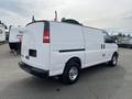 White 2013 Chevrolet Express van with a streamlined body and chrome wheels parked with a partially obscured rear view