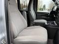 The interior of a 2021 Chevrolet Express featuring two fabric seats with armrests and a central console with cup holders