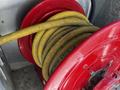 A red hose reel with yellow and black hoses coiled around it is partially visible in the foreground