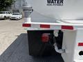 2015 Ford F-750 with a water tank connected to the rear featuring a hose and light on the side