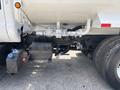 2015 Ford F-750 truck featuring a white fuel tank with various valves and hoses attached to the undercarriage and a visible blue and black component near the rear wheel