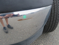 A 2020 Chevrolet Express with a shiny chrome bumper showing a small rust spot on its surface and a tire visible in the image