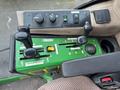 Control panel of a 2014 John Deere 1585 Terrain Cut featuring levers and buttons for operation and adjustment in green and black colors