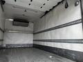 A 2018 Isuzu NRR box truck with an empty interior featuring metal tracks along the walls and a flat wooden floor
