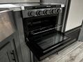 A black oven with a glass door and a metal rack inside is open, featuring control knobs above it for temperature adjustment