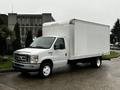 A 2017 Ford Econoline box truck with a white cargo area and a silver front grille parked on a wet surface