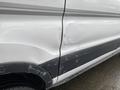 A 2018 Ford Transit with a noticeable dent and scratches on the side door with raindrops visible on the surface