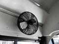 A black ventilation fan mounted on the interior wall of a blue school bus