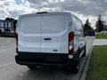 A 2018 Ford Transit van seen from the rear with a white exterior and black lower trim