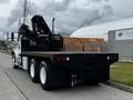 A 2006 Freightliner M2 112 flatbed truck with a black cargo area and a crane attached at the rear