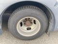 A close-up of the front wheel and tire of a 2016 Chevrolet Express showing the tire tread and a silver rim with visible rust on the lug nuts