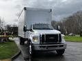 A 2022 Ford F-750 with a large white box truck body parked on a street viewed from the front showcasing its bold grille and headlights