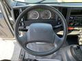 A 2015 Isuzu NPR dashboard with a steering wheel and instrument panel displaying speed and fuel gauges