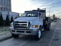 A 2011 Ford F-750 truck with a white cab and a black flatbed parked on a street