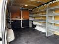 A 2014 GMC Savana cargo van with empty interior space featuring metal shelves on one side and clean flooring