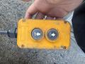 A yellow control box with two circular buttons labeled UP and DN held in a hand