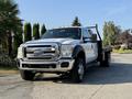 A 2014 Ford F-550 truck with a flatbed and chrome grille parked in a sunny outdoor setting