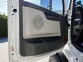 Close-up of the door panel of a 2005 Volvo VND 122 featuring a speaker grille and a handle with a textured black lower section and a light gray upper section