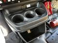 A black console with three cup holders and a storage compartment below found in a 2019 Chevrolet Express