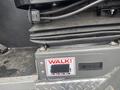 Close-up of a control panel on a 2006 E-One Typhoon with a labeled button that reads WALK and a grey surface with textured detail