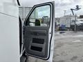 A 2017 Ford Econoline van with the driver's side door open revealing the interior door panel and window