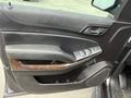 Interior door panel of a 2016 Chevrolet Tahoe featuring controls for windows and locks with a wood trim accent