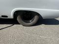A gray 1962 Ford F-100 with a flat black tire and a partially visible side view of the bodywork